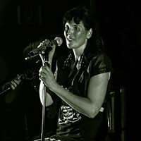 Eine Sängerin singt lächelnd an einem Mikrofonständer