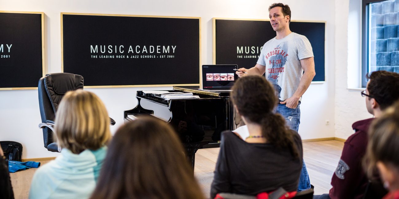 Vocal Coach Mischa Züwerink erklärt einer Gruppe von Workshopteilnehmern wie freies und leichtes Singen funktioniert