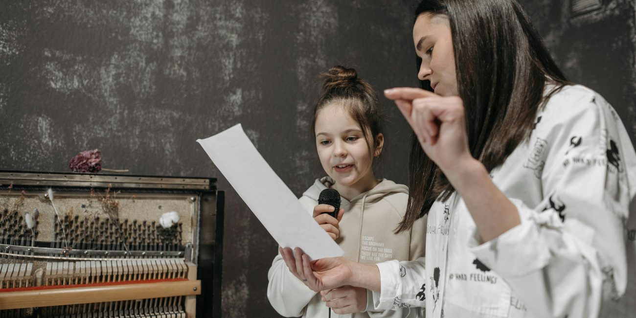 Eine Gesangslehrerin bringt einer Schülerin das Singen bei